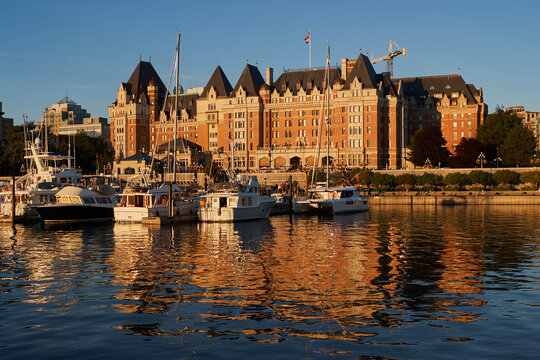 Boats docked in front of the historic Fairmont Empress Hotel at sunset in Victoria, Vancouver Island, Canada.