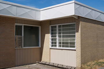 A beige brick wall with a barred window and concrete ground under sunlight in Hope, British Columbia, Canada.