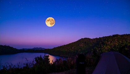 Full moon over a tranquil lake nestled in a mountain valley at twilight