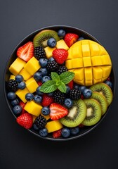 A vibrant fruit bowl filled with mango, kiwi, strawberries, blueberries, and blackberries