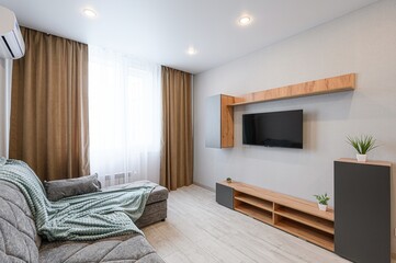 Cozy living room with grey sofa, TV, wooden furniture, and neutral tones