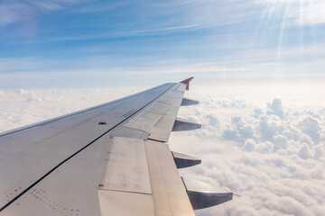 Fototapeta premium View from the airplane window at a beautiful cloudy sky and the airplane wing