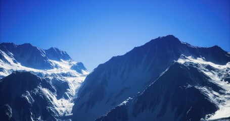 Towering mountain range with snow covered summits against a clear blue sky, showcasing the beauty of natures rugged terrain during daytime, inviting exploration and adventure.