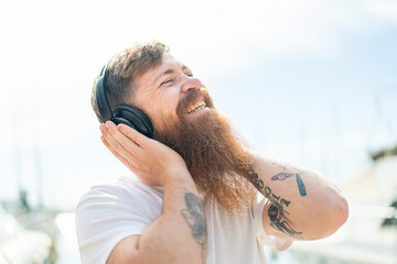Redhead man with beard listening music and singing