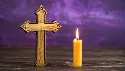 Wooden cross and candle on a wooden surface, purple backdrop