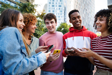 Cheerful young students sharing funny social media content on smartphones