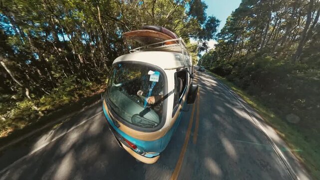 Hippie bus with surfing boards on its roof moves on the street in Brazil