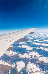 Obraz premium View from the airplane window at a beautiful cloudy sky and the airplane wing
