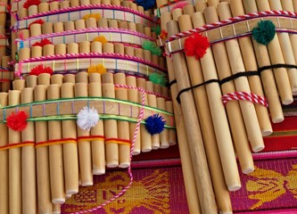 Colorful Andean panpipes laying on a vibrant textile, representing Peruvian culture and music