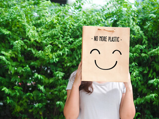 Woman hand holding brown paper bag on green background. Eco friendly bags. Eco friendly concept.