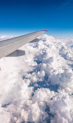 Fototapeta premium View from the airplane window at a beautiful cloudy sky and the airplane wing