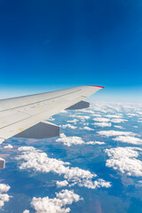 Fototapeta premium View from the airplane window at a beautiful cloudy sky and the airplane wing