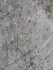 The image shows a close-up of a weathered, textured surface, likely concrete or stone, with cracks, dirt, and discoloration.
