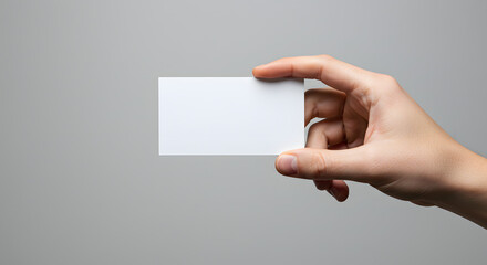 Clean presentation of a blank business card held in a person's hand against neutral gray backdrop ideal for visual