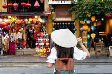 Happy Asian tourist woman wearing Non La (traditional Vietnamese hat) enjoy sightseeing in Hoi An...