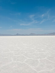 Cracked white surface of the Bonneville Salt Flats stretching toward distant mountains under a...