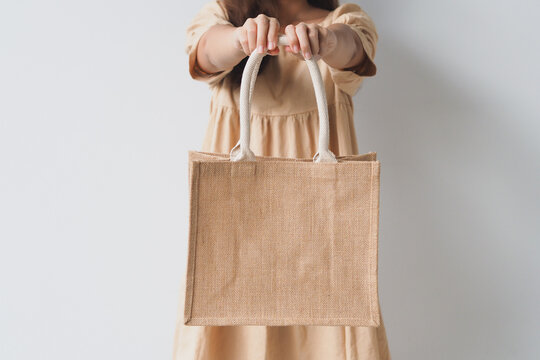 Woman holding  jute bag or sack bag on white background. Reusable shopping bag. Natural material. Zero waste. Plastic free. Eco friendly concept.