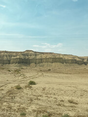 Desert scenery along Route 24 in Utah, with rocky formations in the distance and sparse vegetation under a clear blue sky.