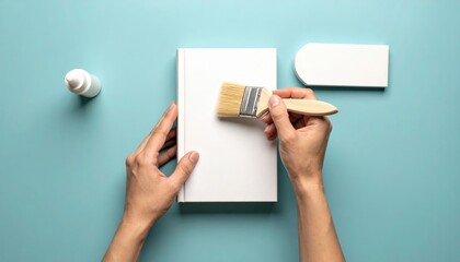 Hands Applying Glue To White Book Cover With Paintbrush