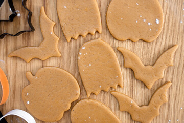 Halloween gingerbread cookies on a wooden background. Homemade cookies for Halloween party - pumpkin, ghost, bat, mummy, skeleton. Halloween background. Top view
