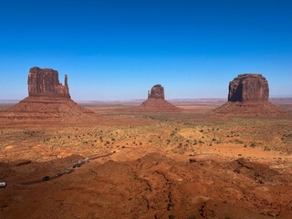 Scenic panorama of Monument Valley with towering red sandstone buttes and desert terrain under clear skies.