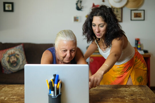 One woman teaches another to use the computer. The two women are thirty-eight and seventy years old respectively and are of Caucasian origin