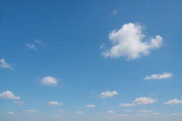 Naklejka premium A serene expanse of blue sky dotted with fluffy white clouds, symbolizing tranquility and endless possibilities