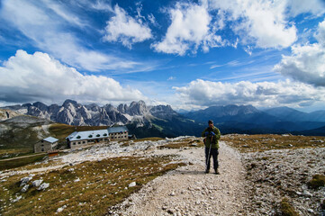 Naklejka premium A trekker enjoying the beautiful view Bolzano across the Catinaccio in the Dolomites, Italy