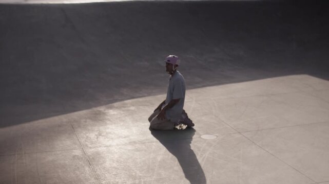 Exhausted inline skater sits tired on skatepark ramp in shadow