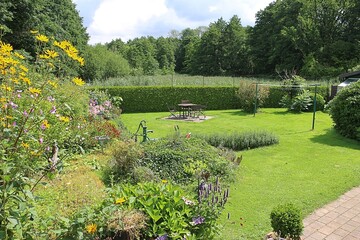 Shot of a pretty green well-kept garden with colorful flowerbeds in a quiet landscape and a small seating area