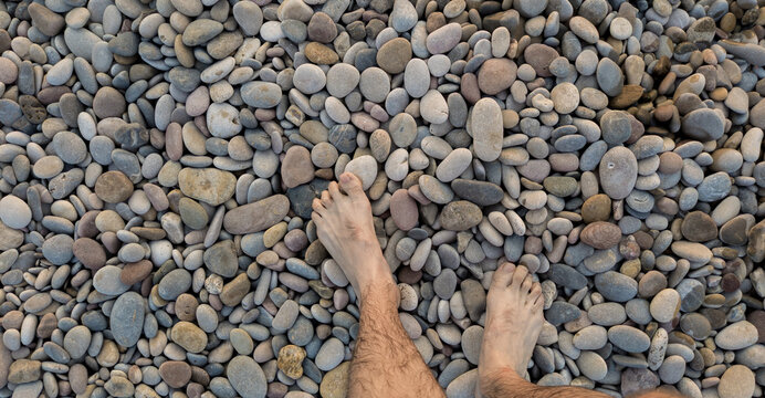 Pies caminando sobre piedras de r&iacute;o.