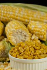 Canned Sweet Corn In Bowl Surrounded By Fresh Corn Cobs.