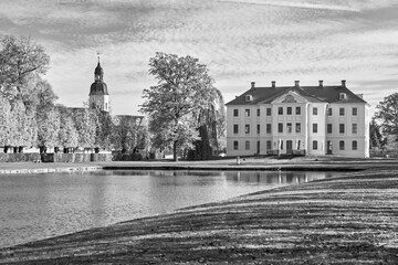 Park with a lordly castle behind a pond in autumn, blackwhite