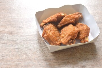 crispy fried salty chicken wing arranging in papay tray packaged on table
