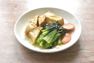 stir fried Chinese cabbage with needles mushroom and carrot topping tofu in soy sauce on plate