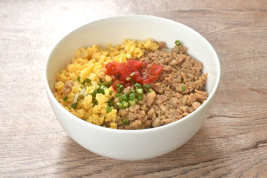 fried chop chicken and sweet egg toppiing red pickled cucumber on rice or tori soboro don japanese food in bowl