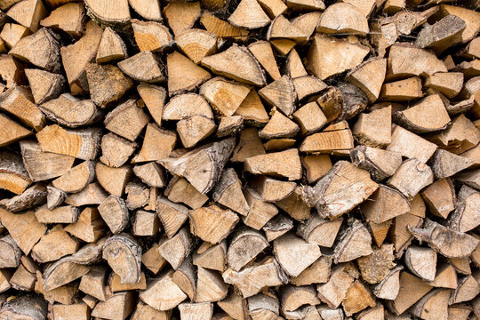 A woodpile of firewood lies in a pile, chopped for burning in the oven.Preparation for winter. A pile of logs for firewood. Background with firewood.Buying and selling firewood for winter