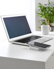 Fototapeta premium Minimalist workspace featuring laptop, smartphone charging, and a refreshing plant