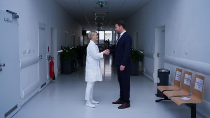 Doctor meeting pharmaceutical representative and shaking his hand, clinical setting.