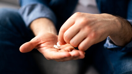 Treatment, medicine, medication, pills, vitamins, supplements concept. Unrecognizable man taking white pills, cropped. Closeup of male hands holding medicine, copy space
