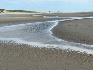 Wasser sammelt sich in wilden Mustern am Strand von Blåvand