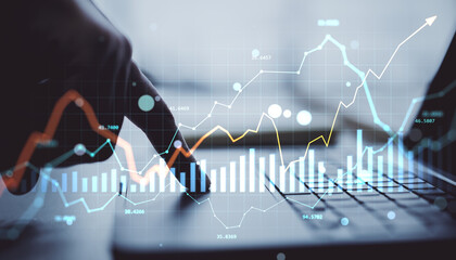 Business hand using laptop with financial chart and currency data visualized as digital hologram on abstract light background for market analysis concept.