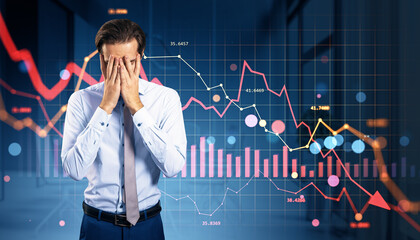 Businessman facepalming in front of crashing financial charts with red downward arrows on digital screen background, symbolizing market collapse.