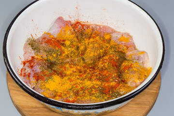 Raw chicken wings sprinkled with different spices for following grilling
