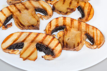 Grilled big button mushroom slices on plate, fragment close-up