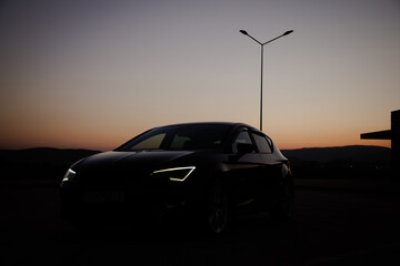 A modern black sport car in the sunset