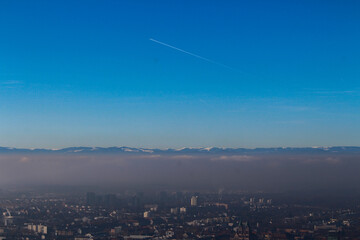 Panoramic view of the foggy city of Freiburg with snow-capped mountain peaks in the background on a winter day