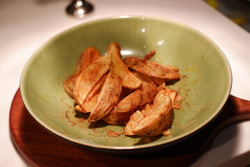 Crispy potato wedges served in a green bowl