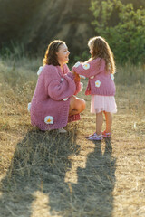 A young mother and daughter are walking in nature among the mountains in beautiful identical sweaters