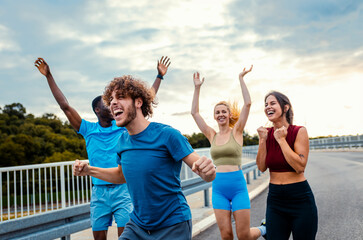 Excited group of people running together on outdoor road.